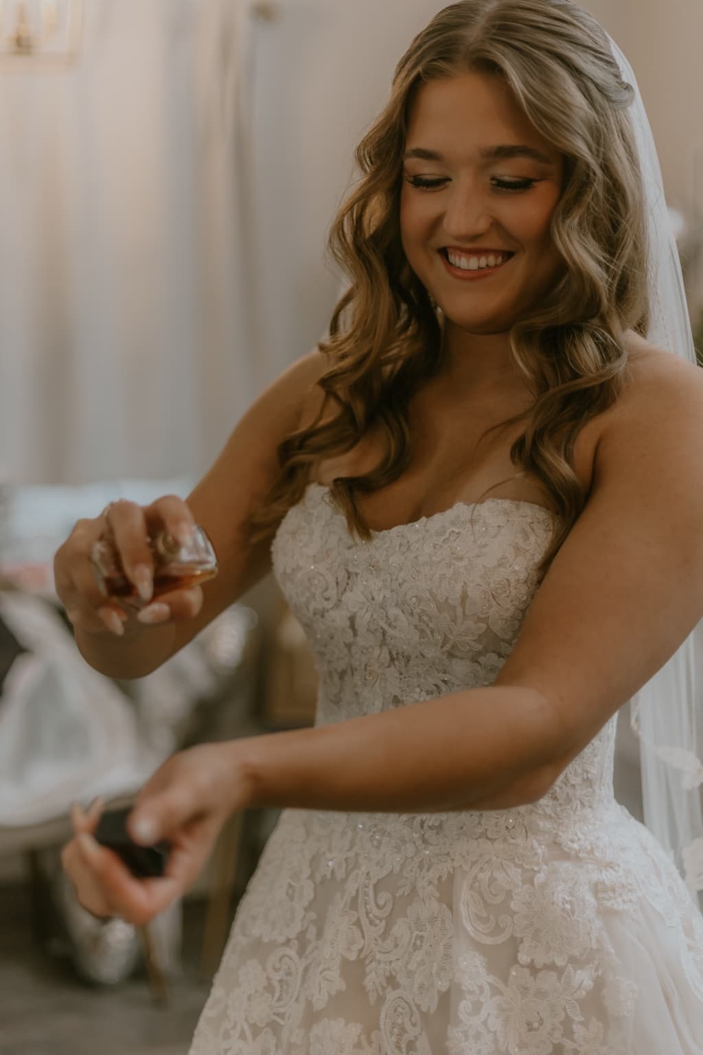 Smiling bride applying perfume while getting ready for her wedding