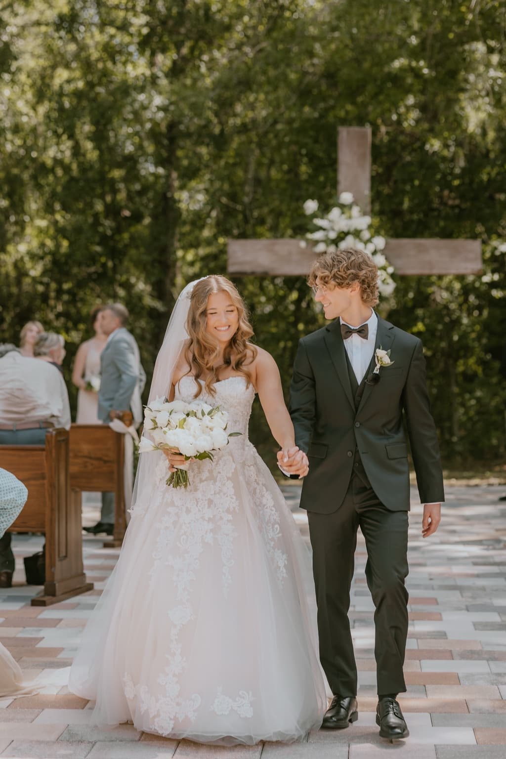Newly married couple walking hand in hand after their outdoor ceremony