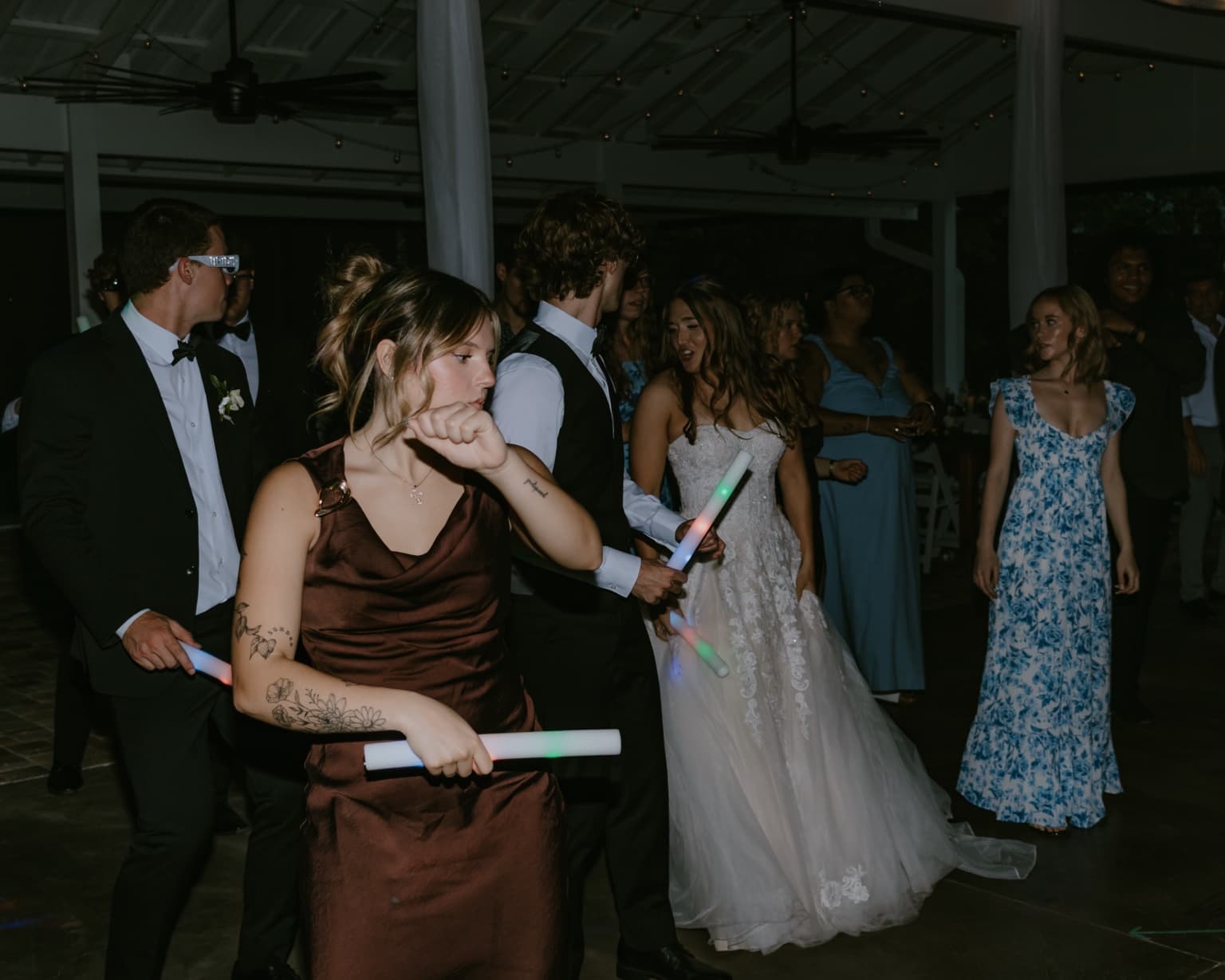 Wedding guests dancing together with glow sticks during the reception