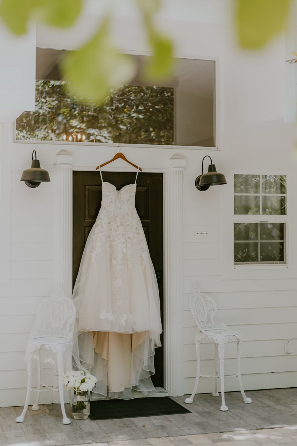 Lace wedding dress hanging outside a white Florida wedding venue